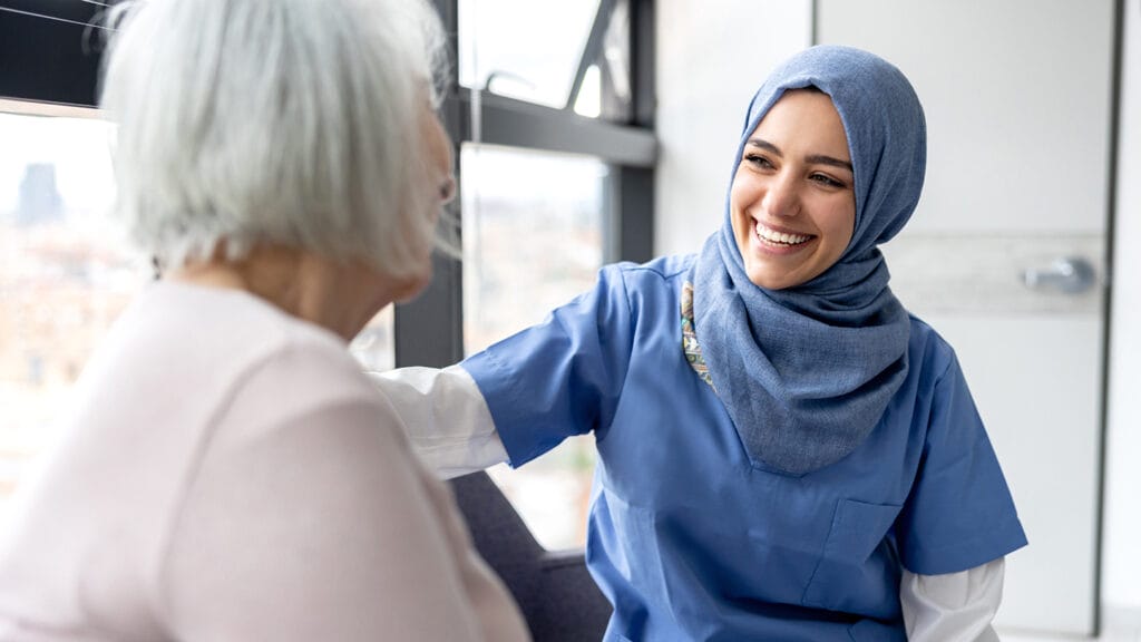 Muslim nurse talking to a senior patient at the hospital and smiling - healthcare and medicine concepts